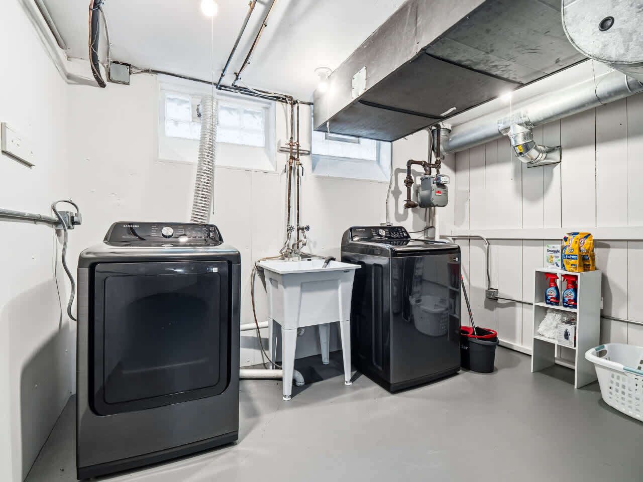 A laundry area with two front-loading washers, a small white table, and a wall-mounted dryer.