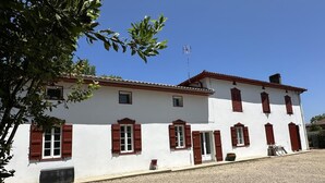 A two-story building with a white facade and red shutters, a gravel driveway, and a clear blue sky. - LACROUTZ - SAINT MARTIN DE SEIGNANX (SAINT MARTIN DE SEIGNANX)