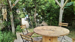 A round wooden table with four chairs, set on a stone patio surrounded by greenery. - LACROUTZ - SAINT MARTIN DE SEIGNANX (SAINT MARTIN DE SEIGNANX)