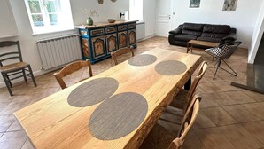 A dining area with a wooden table, chairs, a black sofa, and a cabinet with decorative items. - LACROUTZ - SAINT MARTIN DE SEIGNANX (SAINT MARTIN DE SEIGNANX)