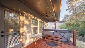 Une terrasse en bois avec un jacuzzi, un ventilateur de plafond et un banc.