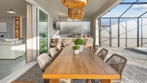Un espace repas moderne avec une table en bois, des chaises en osier et une grande fenêtre.
