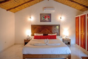 Ein ordentlich eingerichtetes Schlafzimmer mit einem großen Bett, zwei Nachttischen, einer Kopfteil und einer Wand-Klimaanlage.