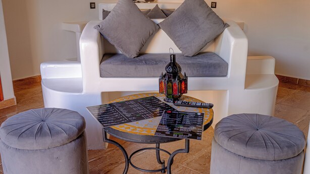 Una sala moderna con un sofá gris, dos otomanas y una mesa de centro con un menú.