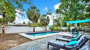 A backyard with a swimming pool, lounge chairs, and a patio area. - Amazing Home with Heated Pool! Sleeps 10! Book Now! Minutes from everything.  (St. Petersburg)