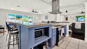 A modern kitchen with a central island, bar stools, a microwave, and a built-in oven. - Amazing Home with Heated Pool! Sleeps 10! Book Now! Minutes from everything.  (St. Petersburg)