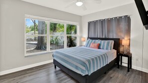 A bedroom with a bed, a window, a ceiling fan, and a nightstand. - Amazing Home with Heated Pool! Sleeps 10! Book Now! Minutes from everything.  (St. Petersburg)