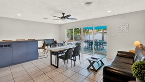A spacious kitchen with a dining area, a black leather sofa, and a ceiling fan. - Amazing Home with Heated Pool! Sleeps 10! Book Now! Minutes from everything.  (St. Petersburg)