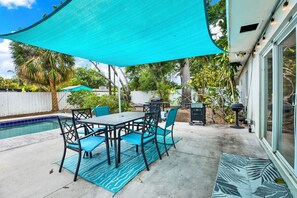 Eine Terrasse mit Pool, Gartenmöbeln und Grillplatz.