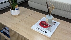 A modern living room with a wooden coffee table, a white sofa, and a potted plant. - Lakeside Hideaway (Lake Ronkonkoma)