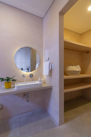 Un bagno moderno con uno specchio rotondo, un lavabo bianco e una pianta in vaso.