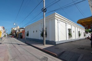 Una strada con un edificio bianco, un marciapiede e un palo della luce.