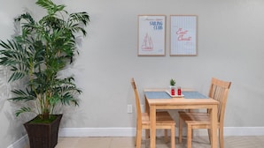 Ein Essbereich mit Tisch und Stühlen, einem Blumentopf und zwei gerahmten Bildern an der Wand.