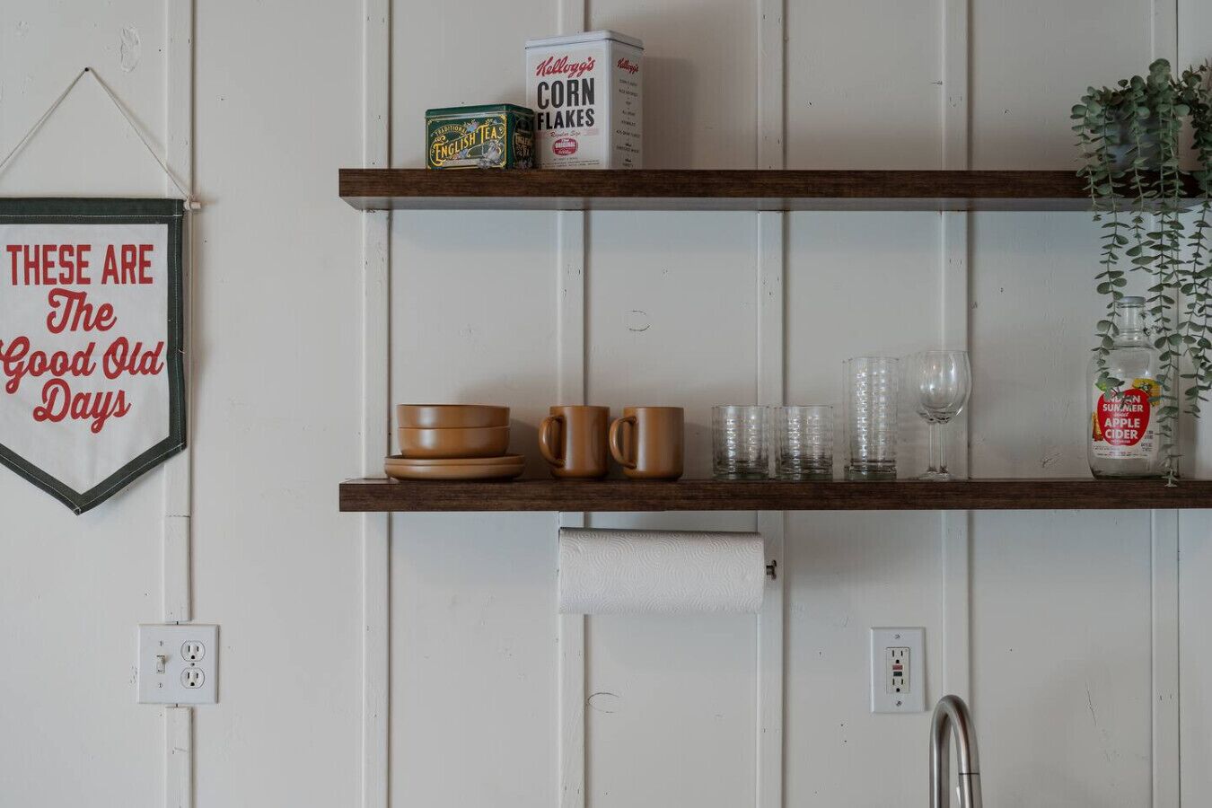 Eine Küche mit Holzböden, die Geschirr, einen Kühlschrank und ein an der Wand befestigtes Schild beherbergt.