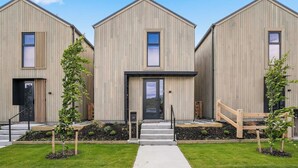 A modern building with three units, each featuring a large window, a door, and a small porch area. - Remarkable Escape | Modern Central Stay Near Airport (Queenstown)