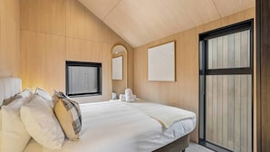 A bedroom with a large bed, a window, a mirror, and a sliding door. - Remarkable Escape | Modern Central Stay Near Airport (Queenstown)