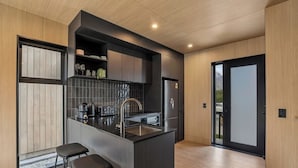 A modern kitchen with a central island, bar stools, a refrigerator, and a sink. - Remarkable Escape | Modern Central Stay Near Airport (Queenstown)