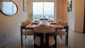 A dining area with a large table set for six, a large window with a view, and a mirror on the wall. - Luxury 3 Suites - Av Annakhil - Panoramic View (Rabat)