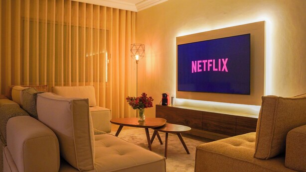 A modern living room with a large flat-screen TV displaying "NETFLIX" in pink letters, a cozy sofa set, a small wooden coffee table, and a floor lamp. - Luxury 3 Suites - Av Annakhil - Panoramic View (Rabat)