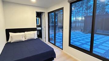 A bedroom with a bed, a large window, and a door leading outside.