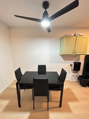 Et spiseområde med et bord, stole, en loftventilator og skabe.