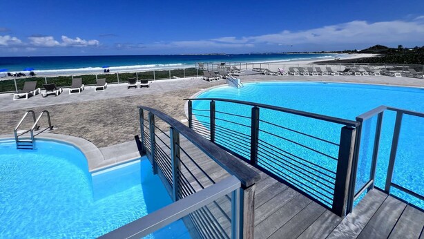 Una piscina con vista a la playa y al océano.