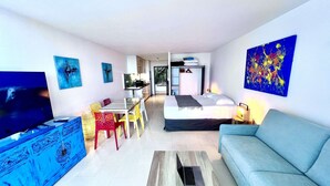 Una habitación de hotel moderna con televisión, zona de comedor, cama y sala de estar.