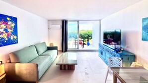 Una sala de estar moderna con sofá, mesa de centro, televisor y un balcón con vistas.