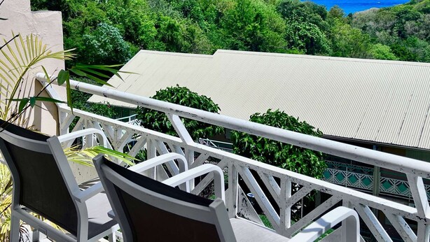 En balkon med udsigt over havet og frodig vegetation.