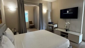 A modern hotel room with a large bed, a desk, a flat-screen TV, and a ceiling fan. - Sunset Paradise Tracadero Apartment: Sea pools access Private Garden WorkSpace (Dominicus)