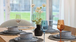 Een eettafel gedekt met borden, glazen en een vaas met bloemen.