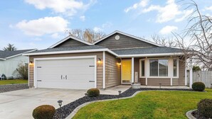 Een twee verdiepingen tellend huis met een garage, een voortuin en een verzorgd gazon.