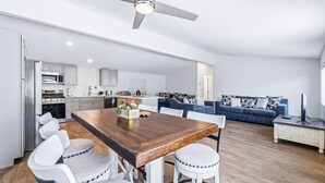 A modern kitchen with a dining area, a blue sofa, and a TV stand. - 4 BDR 2 mins from the River- Sleeps 12 (Bullhead City)