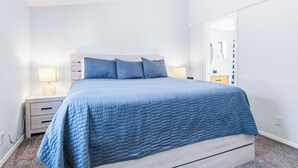 A bedroom with a bed, two bedside tables, a nightstand, a mirror, and a door. - 4 BDR 2 mins from the River- Sleeps 12 (Bullhead City)