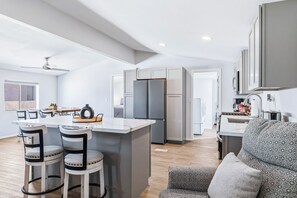 Een moderne keuken met een centraal eiland, barkrukken en een inbouwkoelkast.