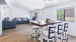 A modern living room with a dining area, a ceiling fan, and a large window with a view. - 4 BDR 2 mins from the River- Sleeps 12 (Bullhead City)