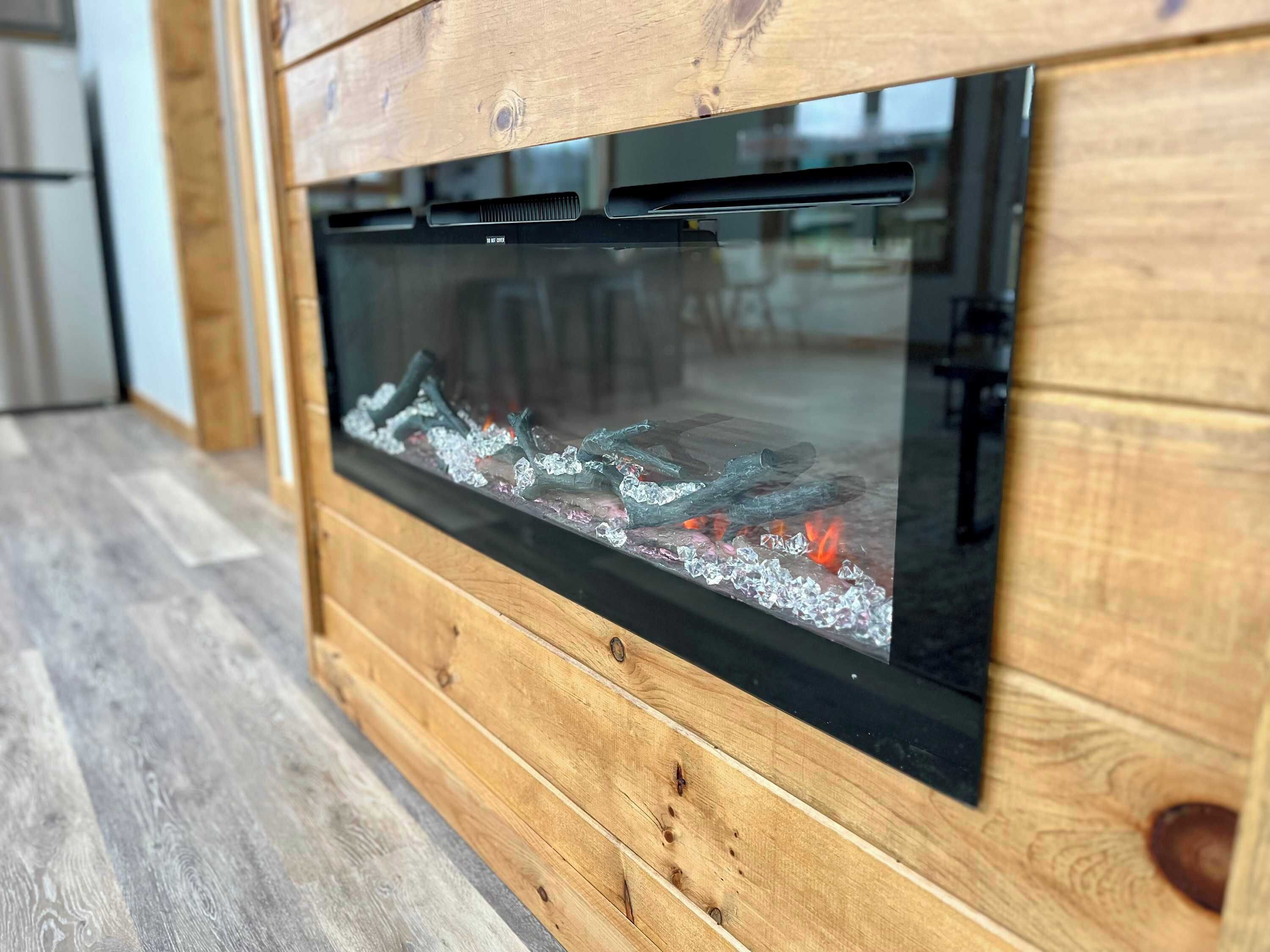 A modern fireplace with a glass front, wooden paneling, and a metal grate.