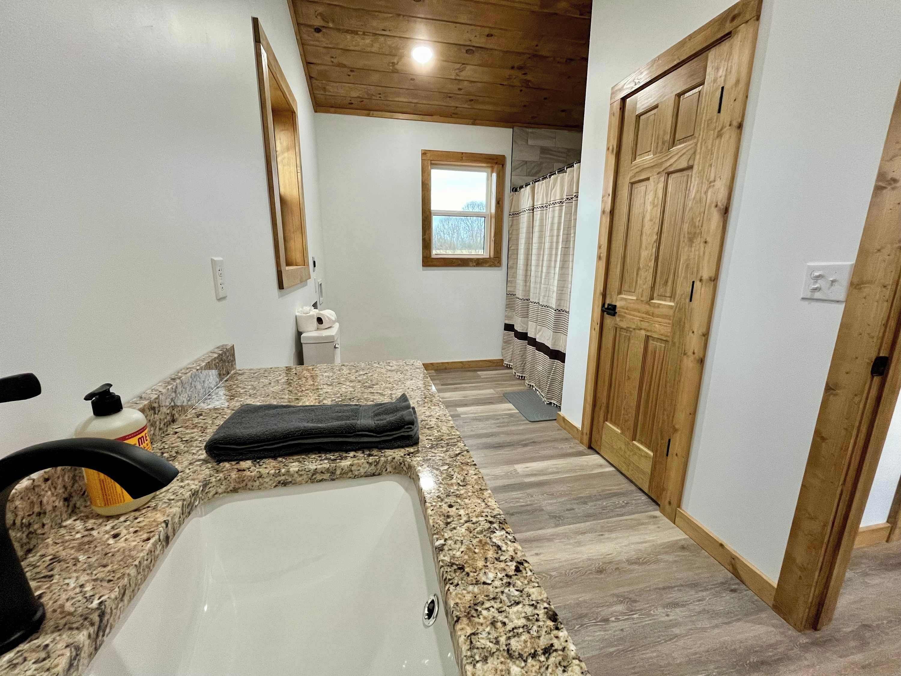 A bathroom with a granite countertop, a sink, a towel, and a wooden door.