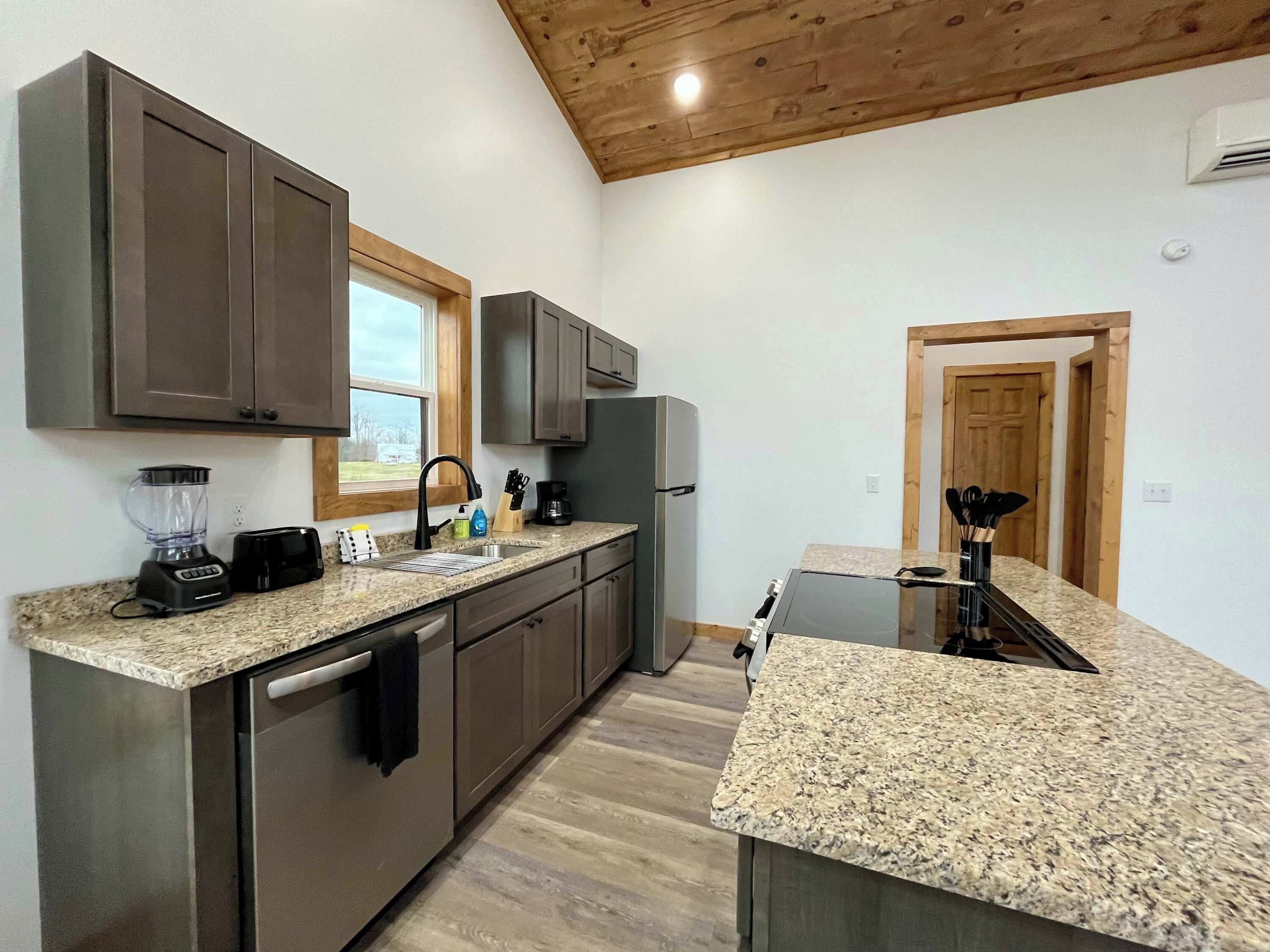 A modern kitchen with granite countertops, stainless steel appliances, and wooden cabinetry.