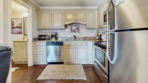 A kitchen with light-colored cabinets, a stainless steel refrigerator, a dishwasher, and a microwave. - Pool + Riverfront! Couples Retreat in Smoky Mtns (Townsend)
