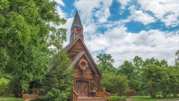 A wooden cabin with a steeply pitched roof, a small porch, and a decorative heart-shaped window. - Pool + Riverfront! Couples Retreat in Smoky Mtns (Townsend)