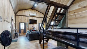 A wooden cabin interior with a bunk bed, a fan, a sofa, and a staircase. - Close to Reelfoot Lake! Dog-Friendly Retreat (Tiptonville)