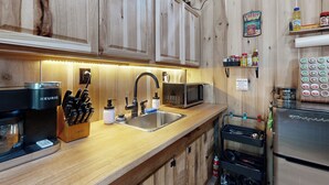 A kitchen with wooden cabinets, a coffee maker, a microwave, and a refrigerator. - Close to Reelfoot Lake! Dog-Friendly Retreat (Tiptonville)