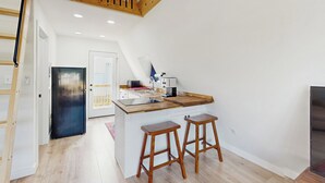 Una cocina moderna con una isla de madera, dos taburetes de bar y un refrigerador negro.
