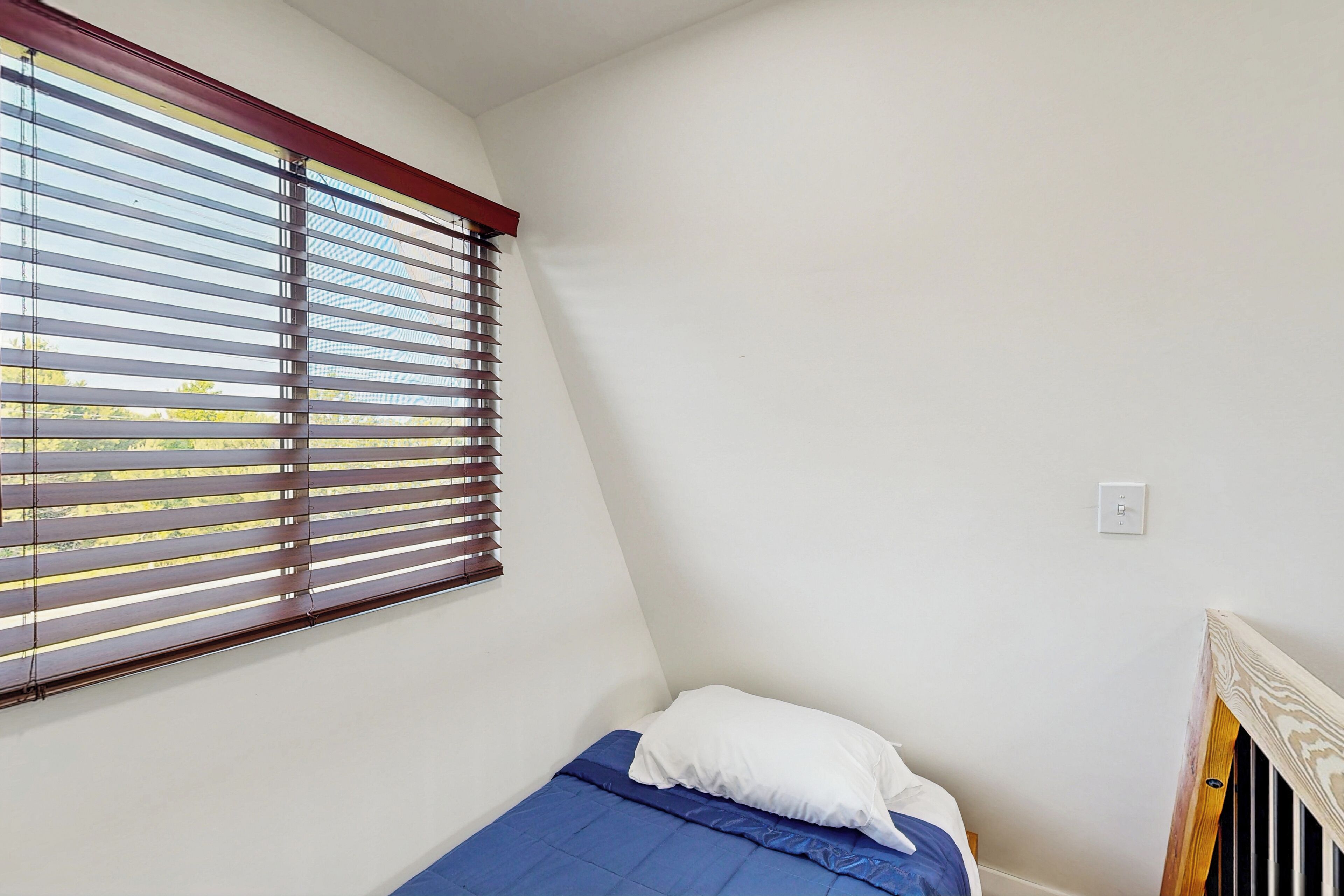 Una habitación pequeña con cama individual, ventana y radiador.