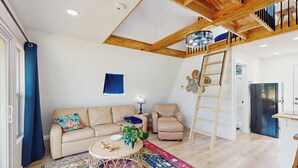 Un salón amplio con techo alto, una escalera de madera, un comedor y una cocina.