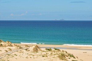 Une plage de sable avec une promenade en bois qui mène à l’eau.