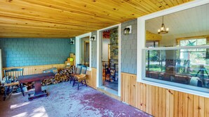A covered porch with wooden flooring, a wooden bench, chairs, and a stone wall. - Hike, Fish, Ski! 'Coos Canyon Lodge' in Maine (Byron)