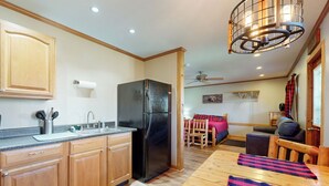 A kitchen with wooden cabinets, a black refrigerator, a wooden dining table with a plaid table runner, and a ceiling fan. - Pet Friendly! Couples Retreat in Southern Illinois (Murphysboro)