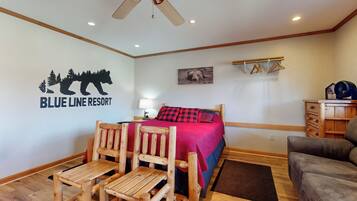 Habitació amb un llit, una cadira de fusta, un sofà, un ventilador de sostre i una paret amb el logotip de 'Blue Line Resort'.